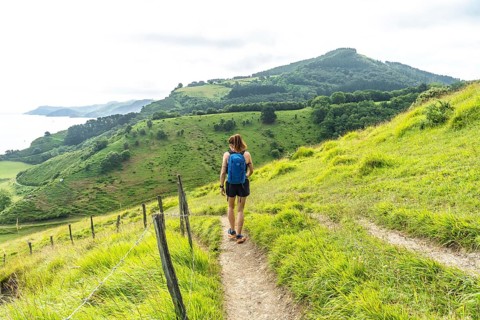 Tourist with backpack enjoying a hike in the basque country near sakoneta beach and its flysch in