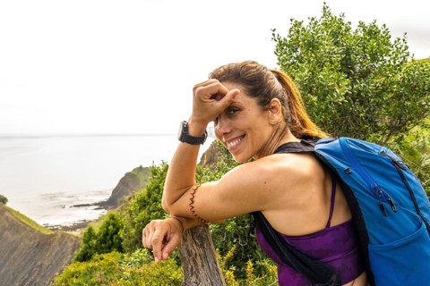 Female hiker with backpack taking a break and enjoying the breathtaking view of sakoneta beach and