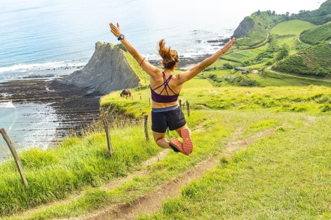 Sportswoman celebrates achieving a fitness goal by leaping in the air with arms outstretched,