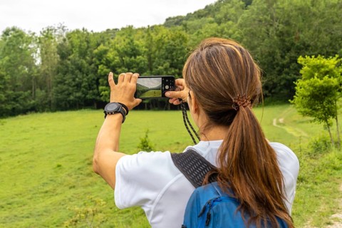 Female hiker taking pictures of the landscape with her smartphone in sakoneta beach area and its