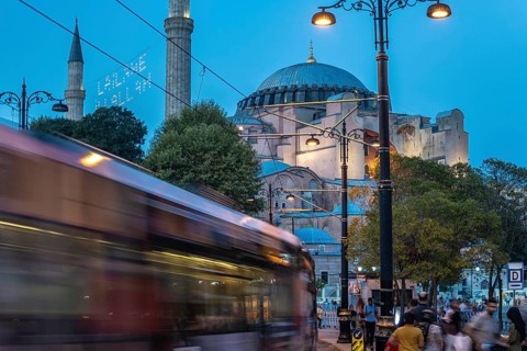 Tram gliding past the iconic hagia sophia in sultanahmet square during the enchanting blue hour in