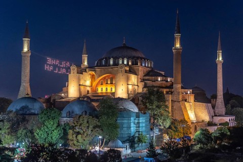 Hagia sophia illuminated at night with a drone light show displaying a religious message in the sky