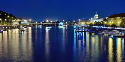 Vltava river reflecting the vibrant cityscape of prague, with boats sailing gracefully on a warm