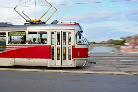 Red and white tram crossing a bridge in prague, creating a dynamic motion blur over the vltava