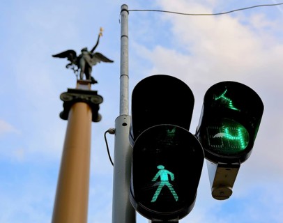 Green traffic light allows pedestrians to cross the street in budapest, hungary, with a statue