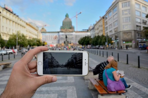 Hand holding smartphone taking photo of wenceslas square in prague, czech republic, with tourists