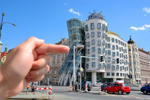 Hand pointing at the famous dancing house in prague, czech republic, a deconstructivist office