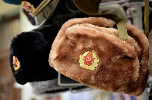 Traditional russian winter hats, known as ushankas, adorned with soviet badges, are displayed for