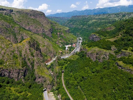 View of valley with roads, tunnels and houses in green mountain landscape, aerial view, landscape
