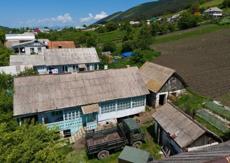 Tractors and implements in a rural setting with fields and mountains in the background, aerial