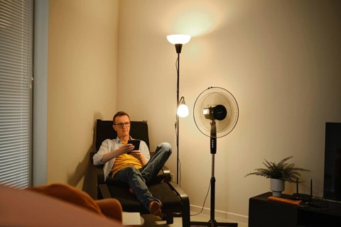 A man sits comfortably in a chair and reading a story on e-book while relaxing in a cozy living