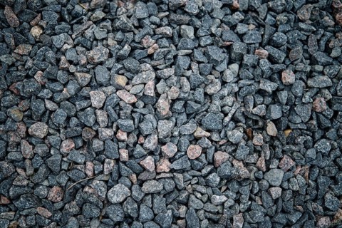 A close-up view of dark gravel featuring small, irregularly shaped stones in shades of gray and
