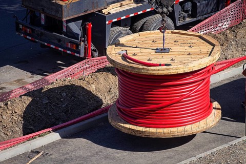 Big red cable coil, rises for installation at the city construction site, no people