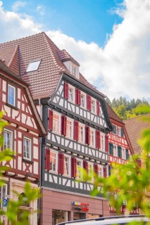 Historic half-timbered house with red shutters under a blue sky, small town of Perle Calw, Black