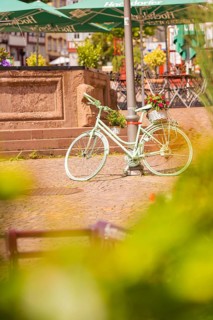 A white bicycle stands decoratively in front of a fountain in the town, small town of Perle Calw,