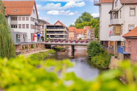Urban river course with bridge flanked by modern buildings and summer flowers, small town pearl