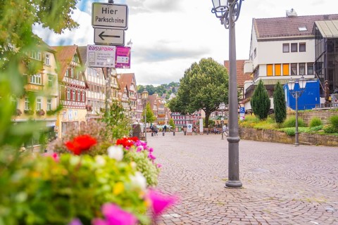 Cobbled street with colourful flowers and historic half-timbered houses, small town of Perle Calw,