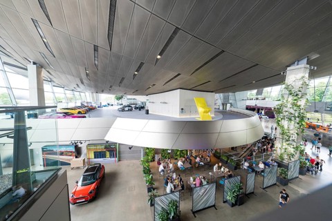 Modern building with seating areas, many plants and exhibited cars, BMW Welt, Munich, Germany