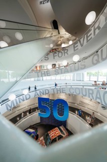 Interior of an exhibition decorated with a curved staircase and large numbers, BMW Welt, Munich,