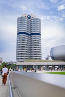 High-rise building next to a modern round building, visited by many people under a partly cloudy
