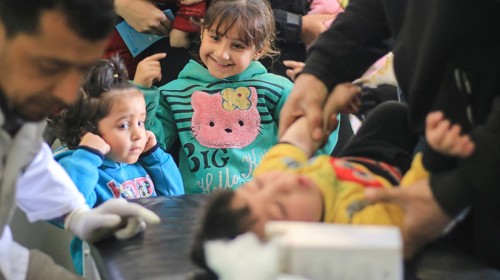 A doctor examining a displaced Syrian child inside a mobile clinic at a refugee camp. Aleppo, Syria
