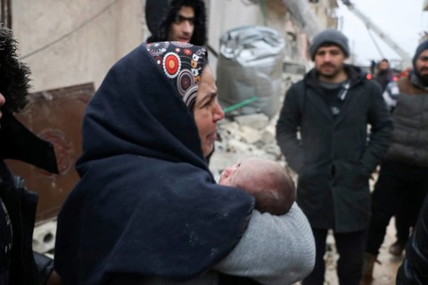 A frightened mother carries her infant after he was pulled from the rubble of a deadly earthquake