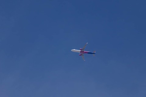 Airbus A321 jet aircraft of Wizz Air airlines in flight in a blue sky, England, United Kingdom