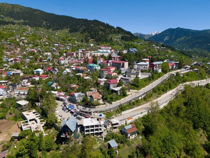 Cityscape embedded in mountains, with colourful houses and lush green surroundings, aerial view,