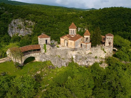 Spacious monastery structure on a rock surrounded by forest landscape, aerial view, Motsameta
