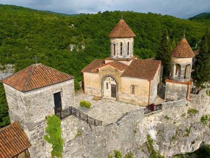 Historic church with tiled roofs on a hill surrounded by dense forest, aerial view, Motsameta