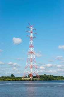 An extremely high electricity electricity electricity pylon, marked white and red, stands on the