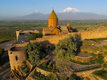 Historic church with stone walls in front of a mountain landscape with blue sky, aerial view, Chor