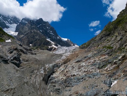 Impressive glacier landscape with rocks and mountains dominated by a clear blue sky and clouds,