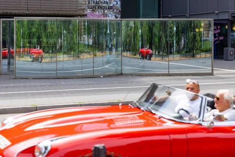 Mirror in front of the Kunsthalle Mannheim. Distorted vehicles are reflected in the glass.