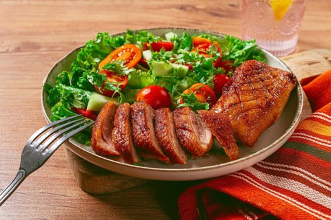 Delicious grilled duck breast served with fresh garden salad and cherry tomatoes at a rustic dining