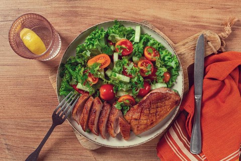 Delicious grilled duck breast served with fresh garden salad and cherry tomatoes at a rustic dining
