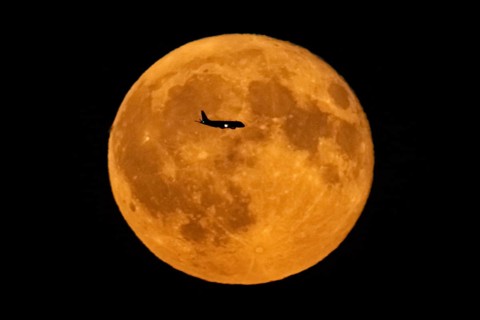 The silhouette of an aeroplane stands out against the full moon, Frankfurt am Main, Hesse, Germany