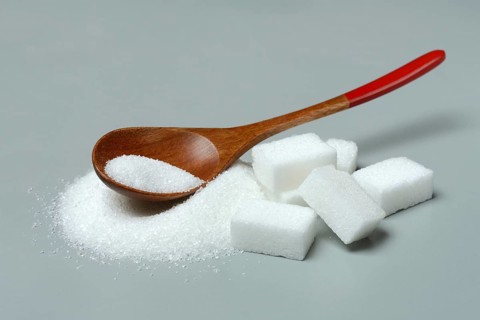 Sugar with wooden spoon and sugar cube