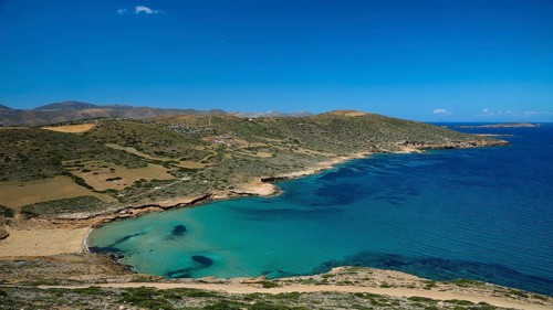 Bay of Vai, coast with crystal blue water, surrounded by hilly landscape under a clear sky,