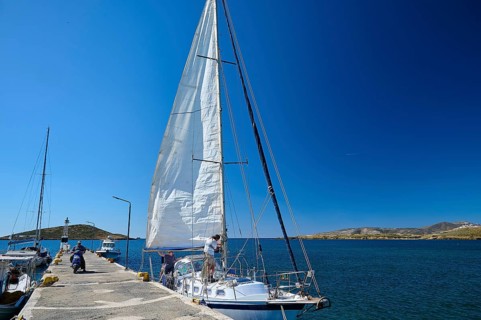 A sailing boat moors in sunny weather at a pier in the deep blue sea, Analipsi, Maltezana,