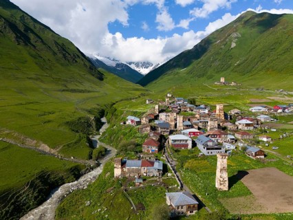 A picturesque village with historic buildings and towers in a green valley between mountains,