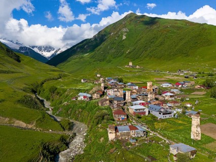 A traditional village with historic towers, embedded in a green mountain landscape, aerial view,