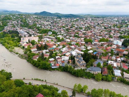 Overview of a hilly cityscape with river, residential buildings and a prominent church, aerial