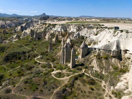 A hilly landscape with iconic rocks and roads in Cappadocia, aerial view, Love Valley, Göreme