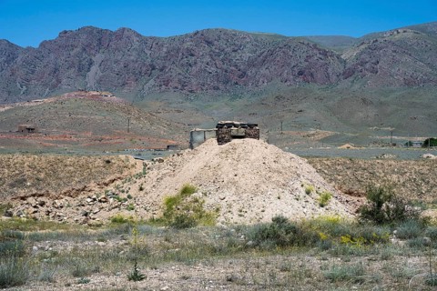 Abandoned-looking bunker on a hill in a mountainous landscape, embrasure on the border to the