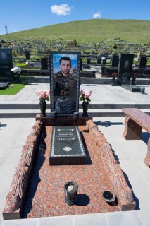 Tomb monument with portrait and flowers, surrounded by green hills and blue sky, Tomb of 2020,