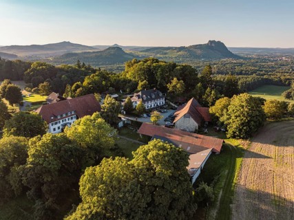 Luftbild von einer Hofsiedlung mit dem Berggasthaus Rosenegg, dahinter die Hegauberge,