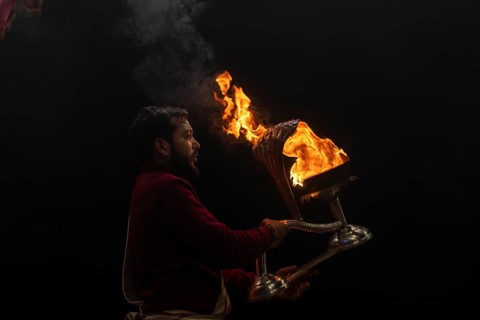 Hindu priest performing the Aarti ritual, holding a burning oil lamp, at the Ganges, Bangali Tola,
