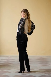 A middle-aged woman stands confidently with her back turned, showcasing a chic black and white