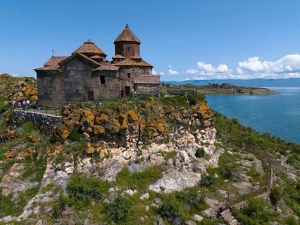 Historic church on a hill overlooking a lake under a bright blue sky, aerial view, Hajrawank